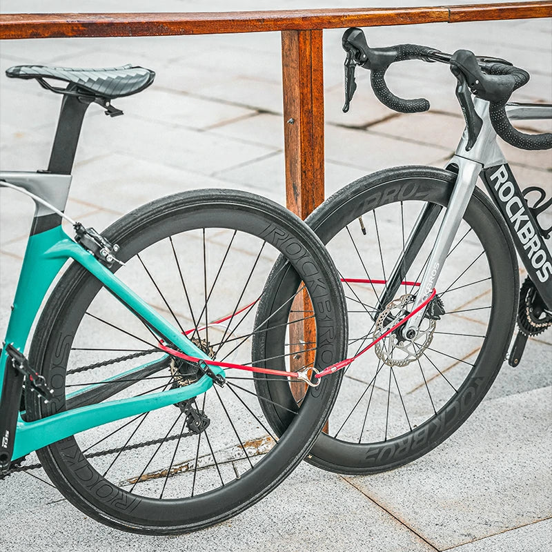 Two bicycles, one teal and one silver with black components, leaning against a wooden railing.