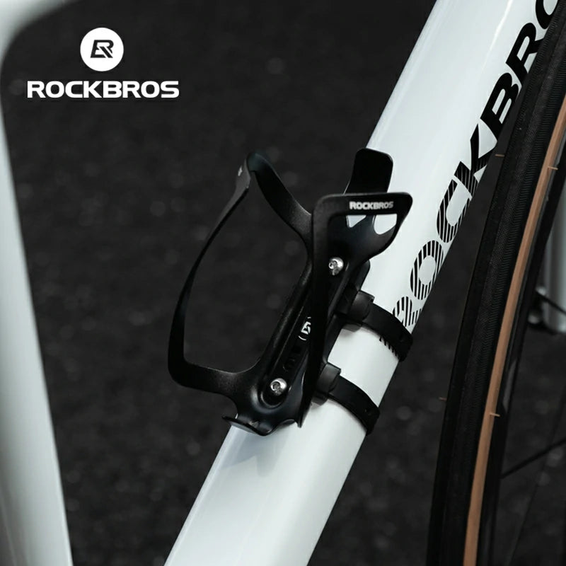 Black bicycle water bottle holder attached to a white bicycle frame with RockBros branding.