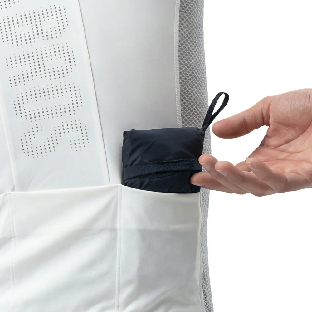 Hand placing a small black item into a white garment with mesh detailing.