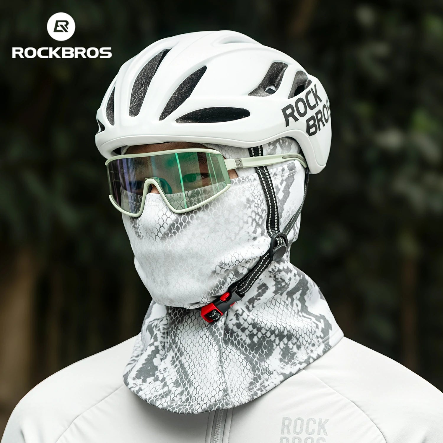 Person wearing a white helmet and face mask with 'RockBros' branding, against a blurred natural background. #color_Serpentine gray