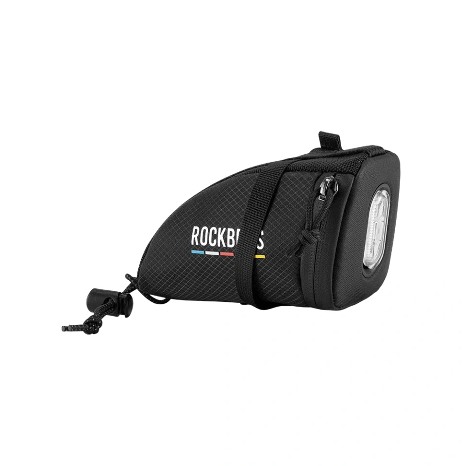 A black bicycle handlebar bag with a front-facing headlight and a mounting plug, shown on a plain white background.