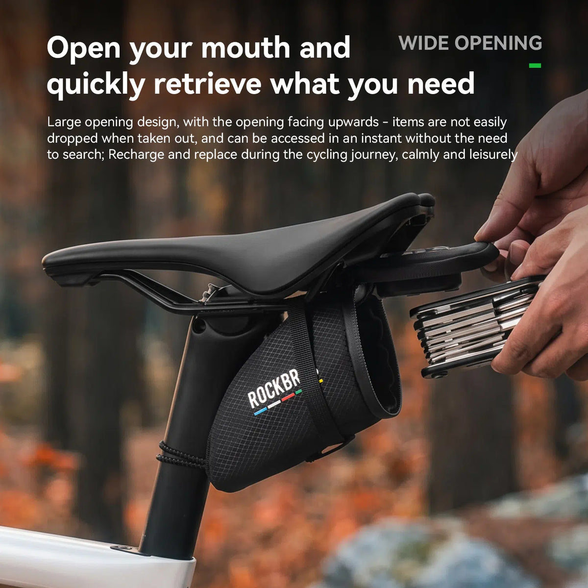 A close-up of a bicycle saddle with a black ROCKBR saddle bag mounted below it, being opened by a person's hands. The image includes marketing text at the top explaining the wide opening design.
