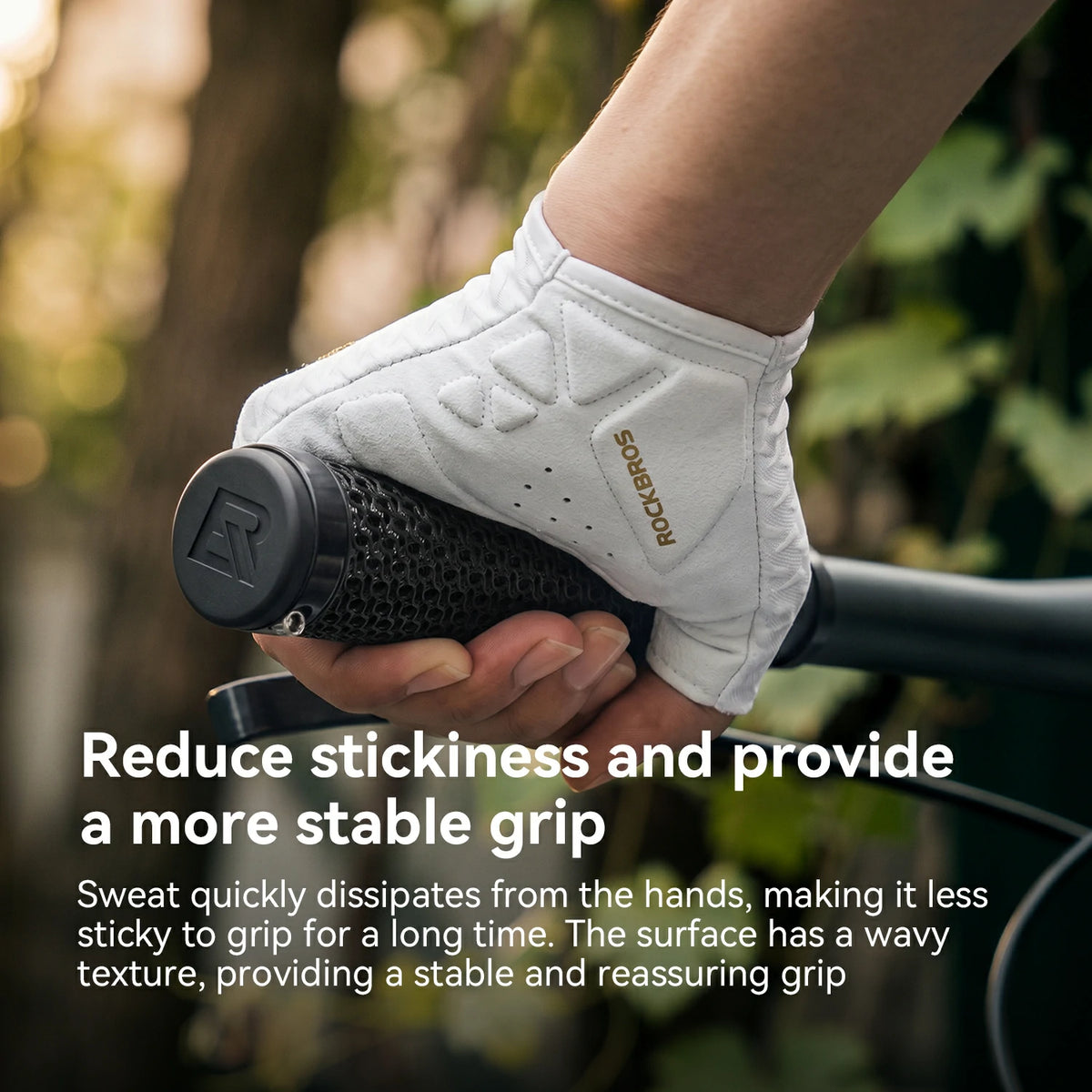 A close-up of a hand wearing a white RockBros cycling glove while gripping a black handlebar in an outdoor setting with blurred trees and foliage. White text at the bottom explains the glove's grip and sweat-dissipation benefits.