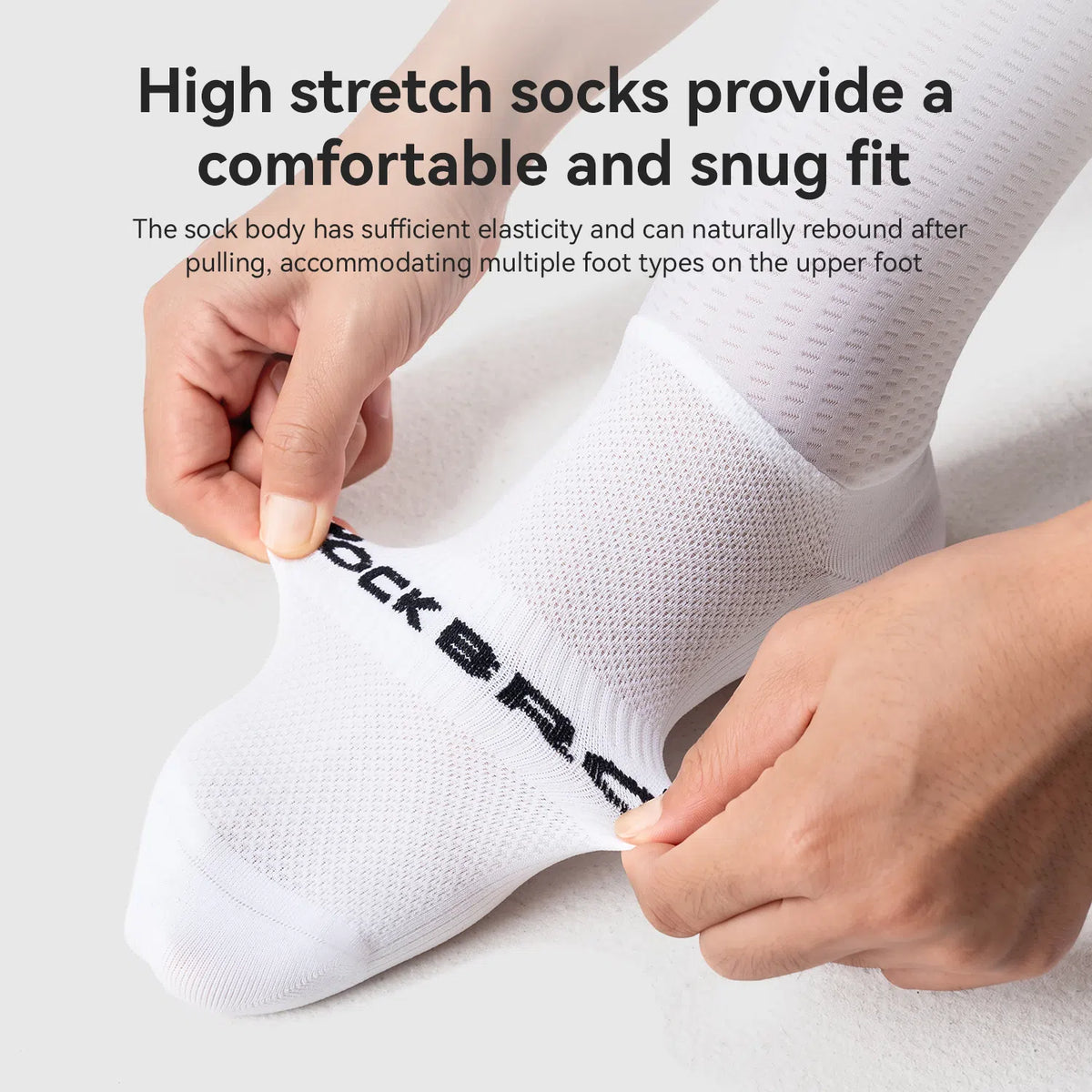 White athletic socks with black 'ROCKBROS' lettering, shown being stretched by hands to demonstrate elasticity, on a light gray background with promotional text.