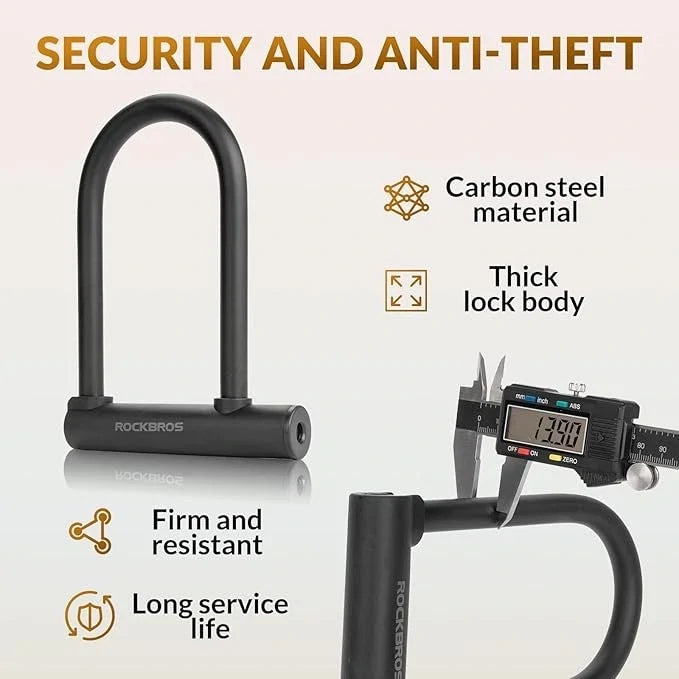 Black Rockbros carbon steel U-lock shown on a light beige background with promotional text and feature callouts, including 'Security and Anti-Theft,' 'Carbon steel material,' 'Thick lock body,' 'Firm and resistant,' and 'Long service life.' A caliper is shown measuring the lock body in the lower right.