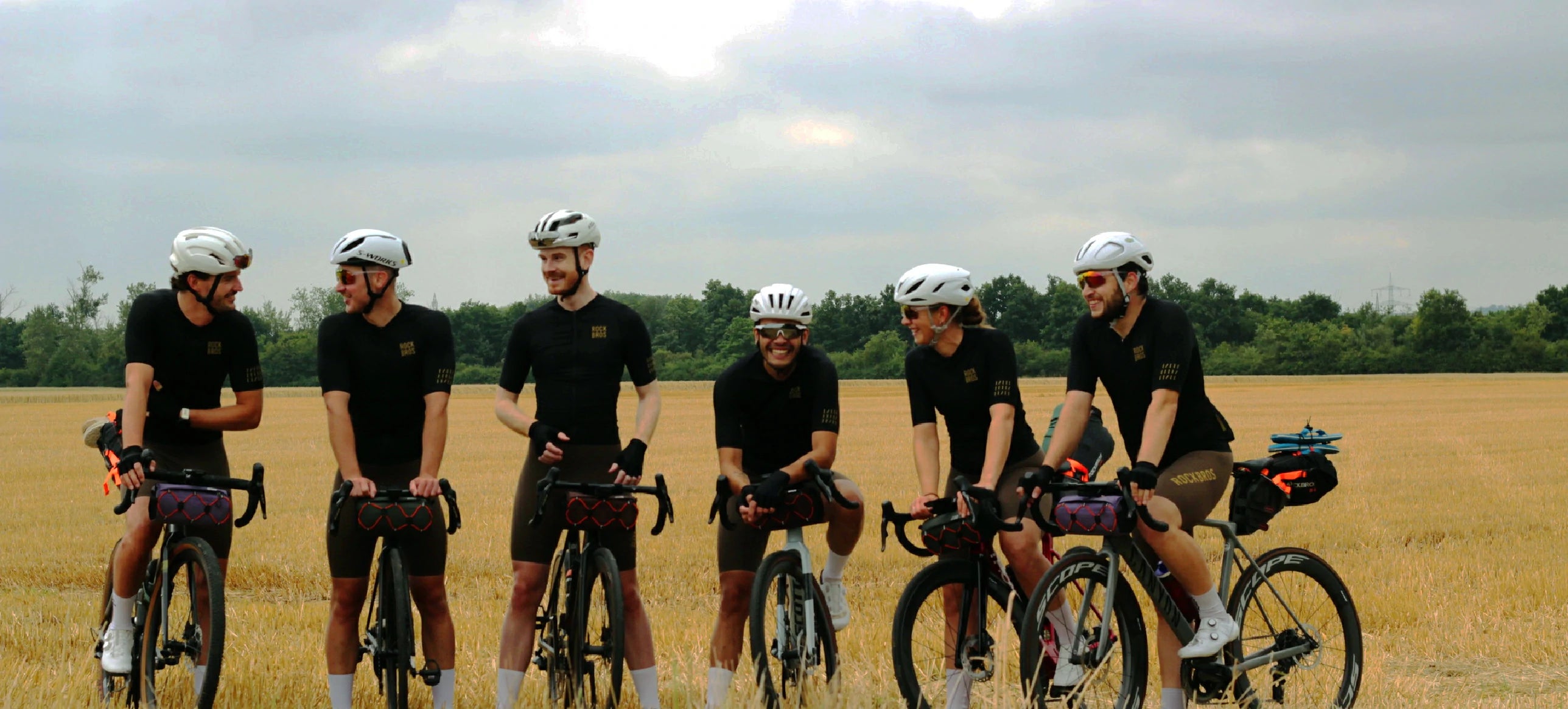 Group of cyclists in a line on a rural road with a clear sky.