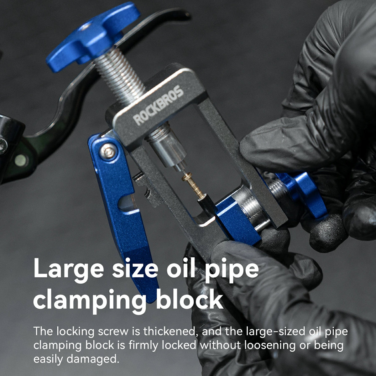 A close-up of a ROCKBROS large size oil pipe clamping block being held by gloved hands on a dark background, with product text overlay explaining its use.