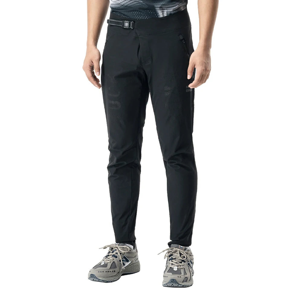 A person wearing slim-fit black technical pants with a black belt, shown from the waist down against a plain white background.