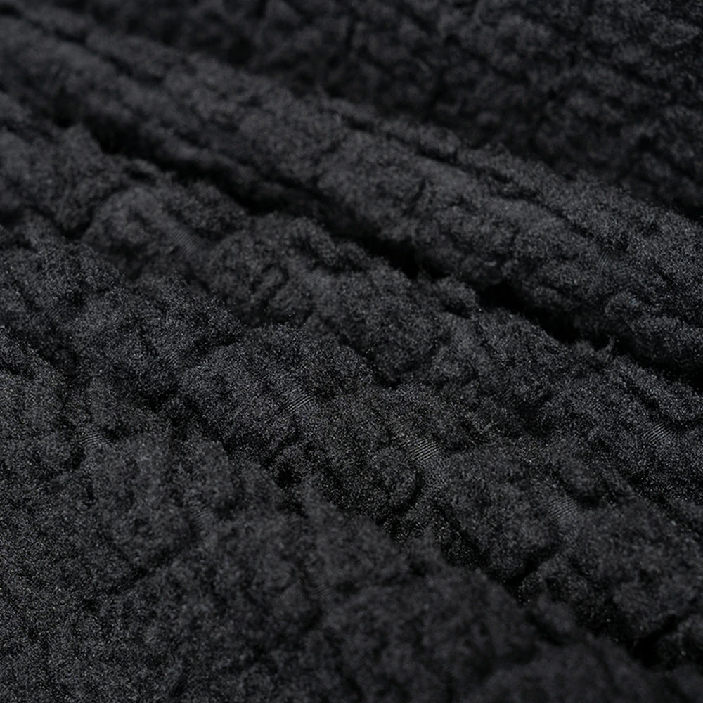 Close-up of a dark charcoal gray or black textured fabric with a ribbed, quilted, or bouclé-like surface.