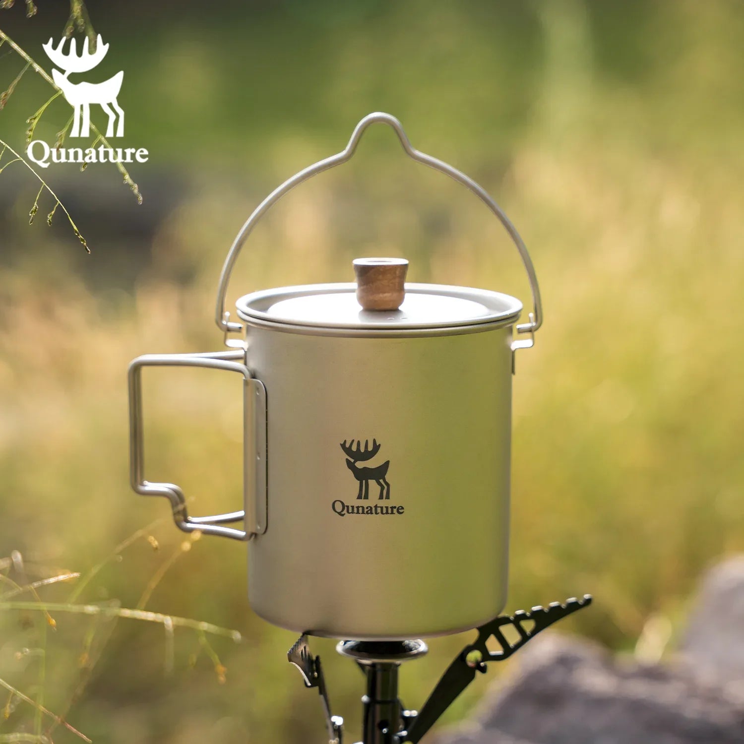 Camping mug with handle on a stand against a natural background, featuring Qunature logo.