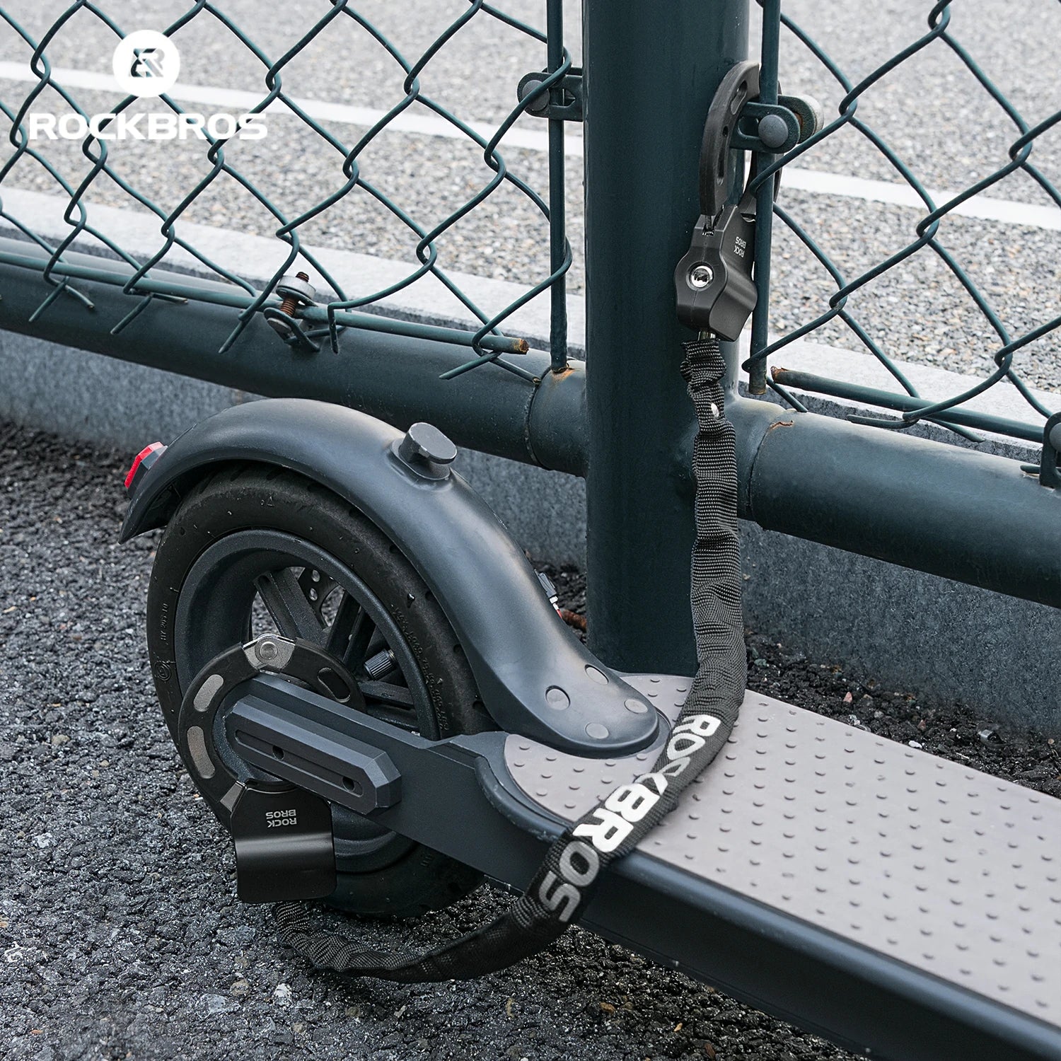 Black scooter with visible branding against a chain-link fence background