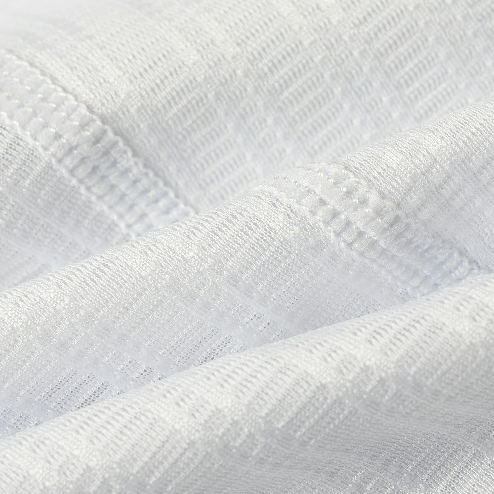 A close-up of white textured fabric with a fine ribbed pattern and soft folds.
