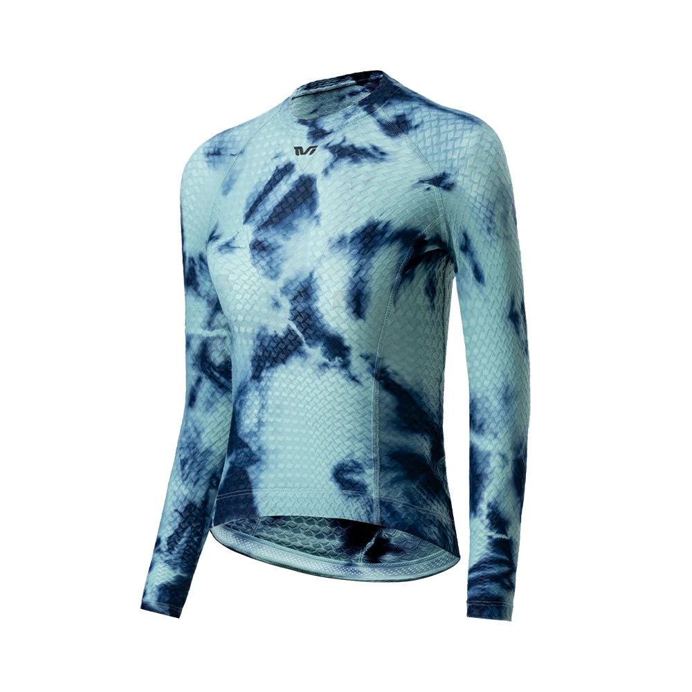 A long-sleeve athletic cycling jersey with a blue and light teal tie-dye pattern, featuring a textured waffle knit fabric and a small black logo on the upper chest, displayed on a clean white background. #Color_Blue